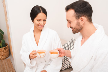 Beautiful mixed race couple drinking relaxing tea at a spa. Romantic date at a spa salon
