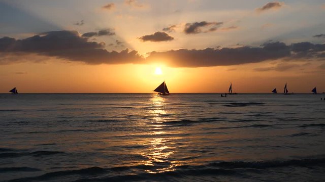 Silhouette Paraw sailing boats under orange sunset at Boracay Island of Philippines 60fps