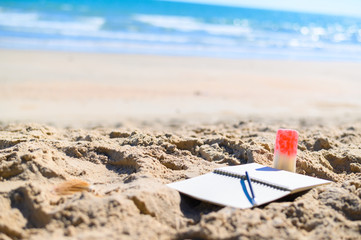 Books with pencils and ice cream on the beach in the Caribbean with copy space.