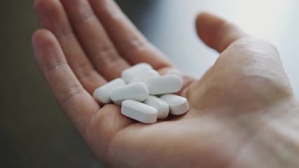 Vitamins and supplements. Man takes white vitamin pills or medicine in hands - Powered by Adobe