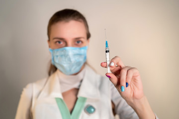 Female doctor wearing protective blue mask, white uniform. Banner epidemic, virus protection. Patients need to get the flu vaccine. Deficiency in medicines and new protective equipment for koronavirus