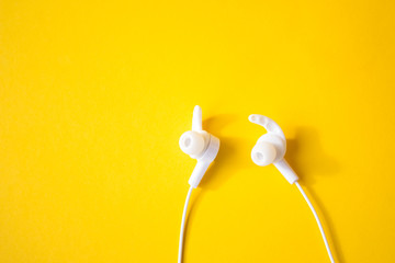 White wired headphones on a yellow background. Colorful spring concept.