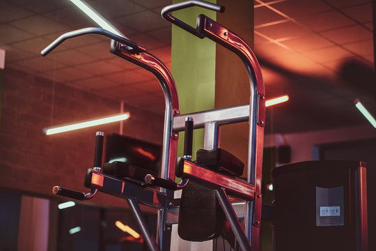 Metallic parallel bar machine standing in an empty modern fitness center. Sportive gym equipment.