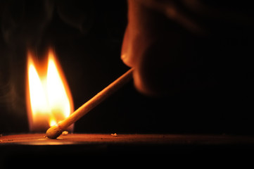 Matchstick ignites with the help of the matchbox with beautiful flames and smoke.