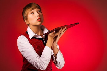 Portrait of a sensitive young girl with envelope for papers on a red background. The concept of advertising office supplies and special offers and discounts. Advertising space
