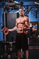 Fototapeta premium Fit mucular bodybuilder doing weightlifts with barbell in a modern fitness center looking questioned