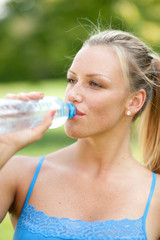 Woman drinking water during her training in the nature