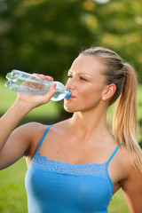 Woman drinking water during her training in the nature