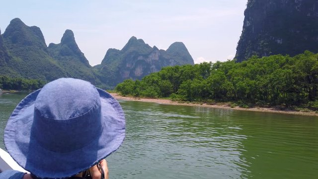 Western female tourist admiring stuning karst scenery on a trip on the magnificent Li river from Guilin to Yangshuo, China
