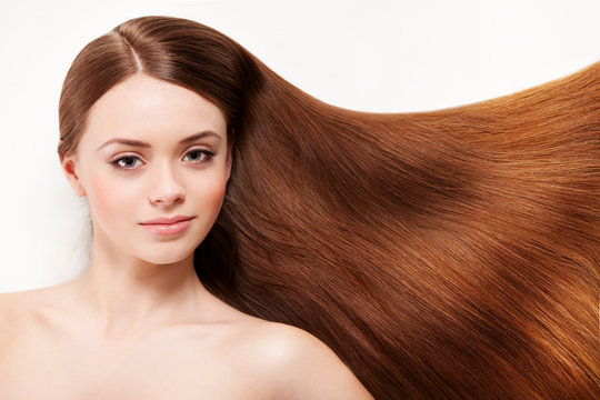 Beautiful woman lying on her back, with her long brown hair on white background, smiling and looking at camera