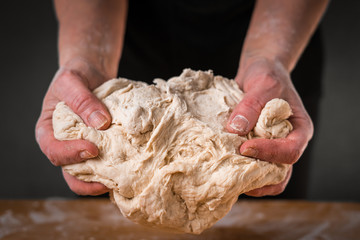 Making dough by female hands on wooden table background close up