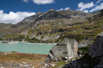 Large stones at the Alpine lake with turquoise water