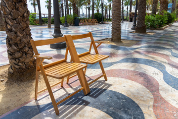 Promenade Explanada the main and famous landmark tourist street Alicante. Two wooden chairs for relaxing.