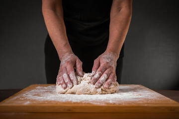 Making dough by female hands on wooden table background close up