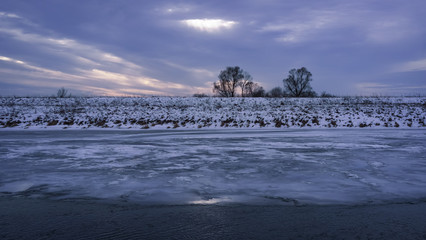 Winter landscape with frozen river and trees in the snow