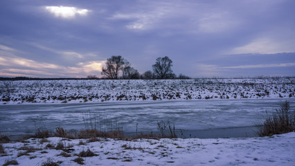 Winter landscape with frozen river and trees in the snow