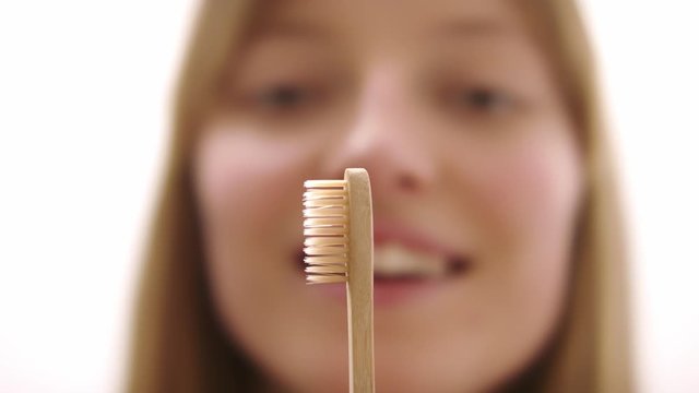 Woman showing eco-friendly bamboo toothbrush. Environmental friendliness and zero waste concept.