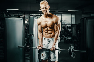 Obraz na płótnie Canvas Bodybuilder strong man pumping up biceps muscles