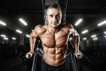 Fototapeta na wymiar Bodybuilder pumping up chest muscles push-ups bars