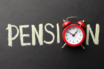 Inscription Pension with alarm clock on black background, top view