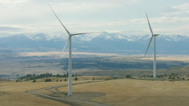Golden plains sit in the shadow of the snow-capped Beartooth mountain Range in southwestern Montana. A group of wind turbines are perched in the foreground