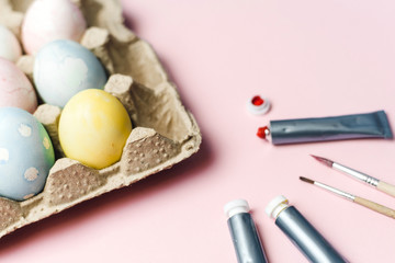 The concept of coloring Easter eggs in pastel watercolor colors. Paints and brushes for coloring eggs for Easter on pink background