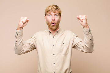young blonde man celebrating an unbelievable success like a winner, looking excited and happy...