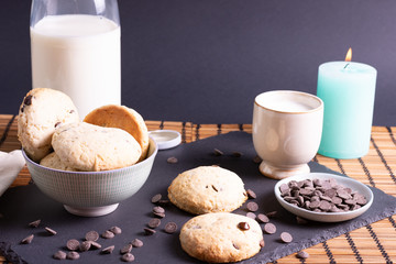 bol con galletas de chocolate pepitas leche en pizarra con vela leche tapón en esterilla en una...