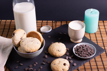 bol con galletas de chocolate pepitas leche en pizarra con vela leche tapón en esterilla en una botella