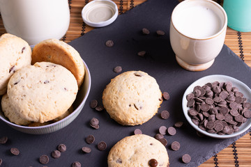 bol con galletas de chocolate pepitas leche en pizarra con vela leche tapón en esterilla en una...