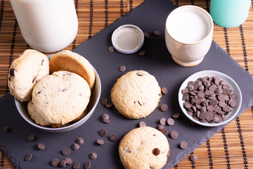 bol con galletas de chocolate pepitas leche en pizarra con vela leche tapón en esterilla en una botella