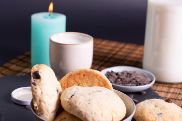 bol con galletas de chocolate pepitas leche en pizarra con vela leche tapón en esterilla en una...