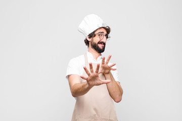 young crazy chef feeling disgusted and nauseous, backing away from something nasty, smelly or...