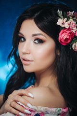 Naklejka premium Beautiful girl with flowers. Spring woman. Lady with bright makeup and a flowering branch in her hair. Spring time. On dark background