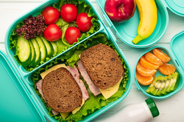 Top view of school lunch boxes with sandwiches and vegetables with fruits: the concept of a healthy and balanced diet
