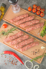 Raw beef sausages. Mititei - Romanian cuisine, on wooden boards with spices. Top view.