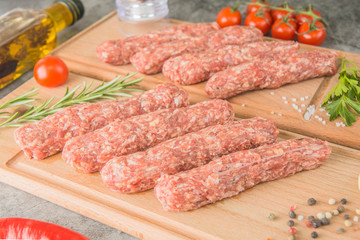 Raw beef sausages. Mititei - Romanian cuisine, on wooden boards with spices. Close-up