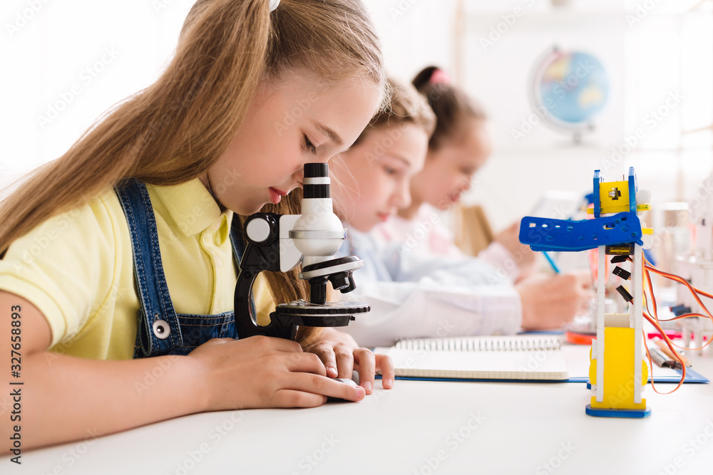 Poster schoolgirl looking at microscope at stem robotic class