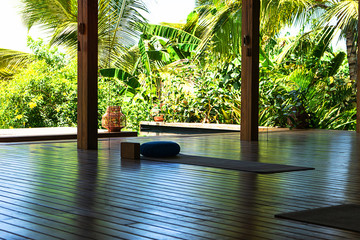Open tropical yoga studio place with view outside to the beautiful garden with palm trees and ocean.