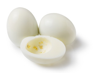 boiled peeled eggs on a white background, two whole eggs, one egg cut in half, half without yolk, concept