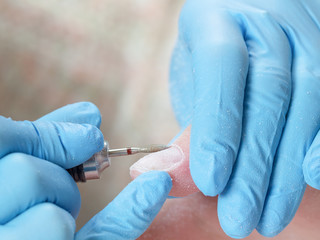 Manicurist polishing nail with electric milling cutter in a beauty salon. Manicure process