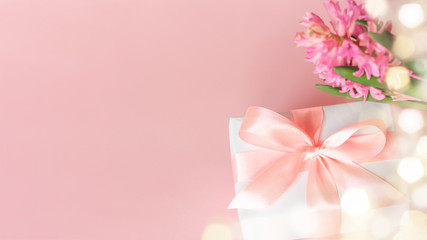 Gift or present box and hyacinth flower on pastel pink background with lights bokeh effect. Copy space. Happy Mother's Day, Women's Day, Valentine's Day or Birthday spring greeting card.