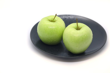 Green apples on a plate isolated on a white background.