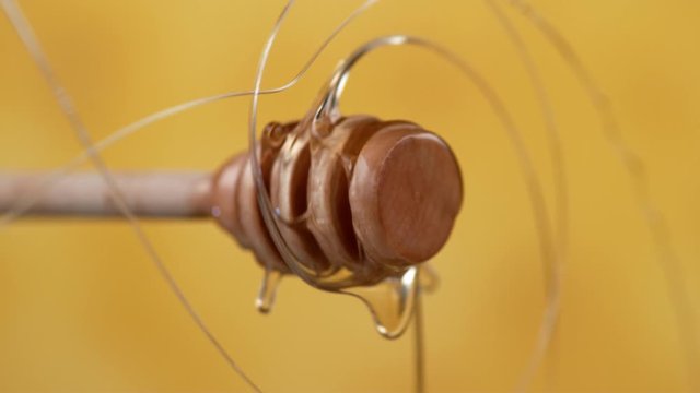 Honey spinning off honey dripper on yellow background.  Shot with Phantom Flex 4K camera.