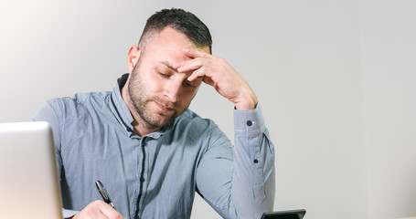 Fototapeta premium Frustrated businessman under stress nervously filling 1040 tax form with calculator at office desk.