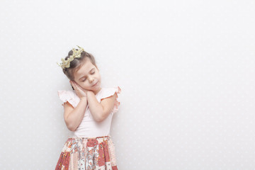 Pretty young girl in pink dress with crown on head dreaming, isolated on pink background. Copy space for your text