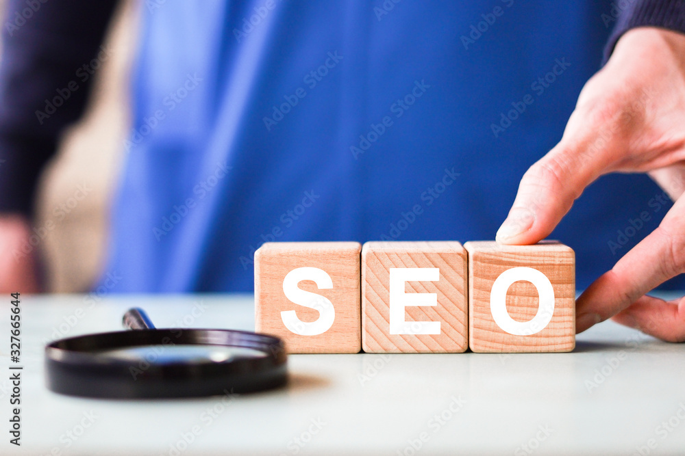 Poster search engine optimization concept. hand putting wood block shape with word seo and magnifier