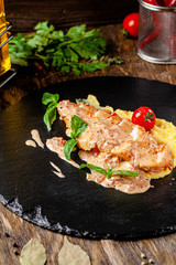 European, Italian cuisine. Roasted chicken fillet with corn porridge, with cherry tomatoes and basel. Serving dishes in a restaurant on black slate. background image, copy space
