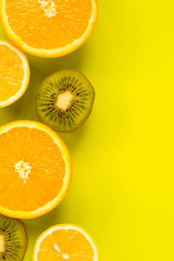 Fruit frame. Colorful fresh citrus fruits on a light green background. Orange, tangerine, lemon and kiwi are cut in half. Flat lay, top view, copy space.