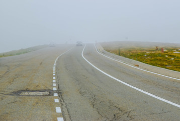 Cars in fog on the Transalpina road DN67C. This is one of the most beautiful alpine routes in...